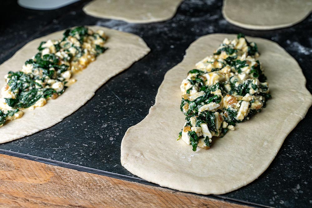 Pide Teig mit Spinat Schafskäse Füllung belegen