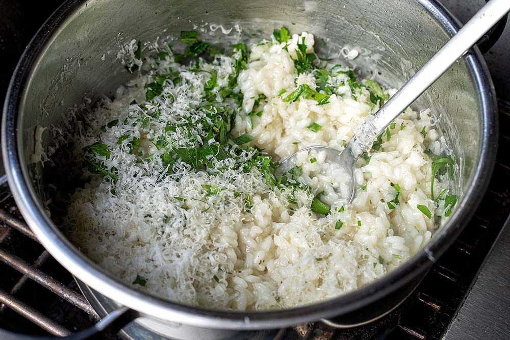 Nun geben wir die Petersilie, den Parmesan und die Butter zum Risotto und würzen dieses mit Meersalz und Pfeffer.