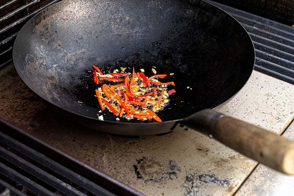 Den Grill mit der optionalen Schickling Grill Wok-Auflage aufheizen und anschließend die Chili-Mischung in dem mit Öl benetzten Wok anbraten.