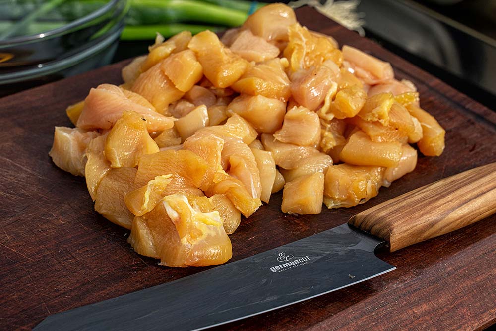 Die Hähnchenbrust unter Zuhilfenahme eines scharfen Messers in Würfel mit einer Kantenlänge von ca. 2 – 3 cm schneiden.