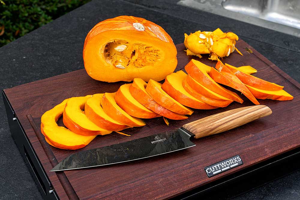 Hokkaido-Kürbis teilen, Fruchtfleisch entfernen, in dünne Spalten schneiden