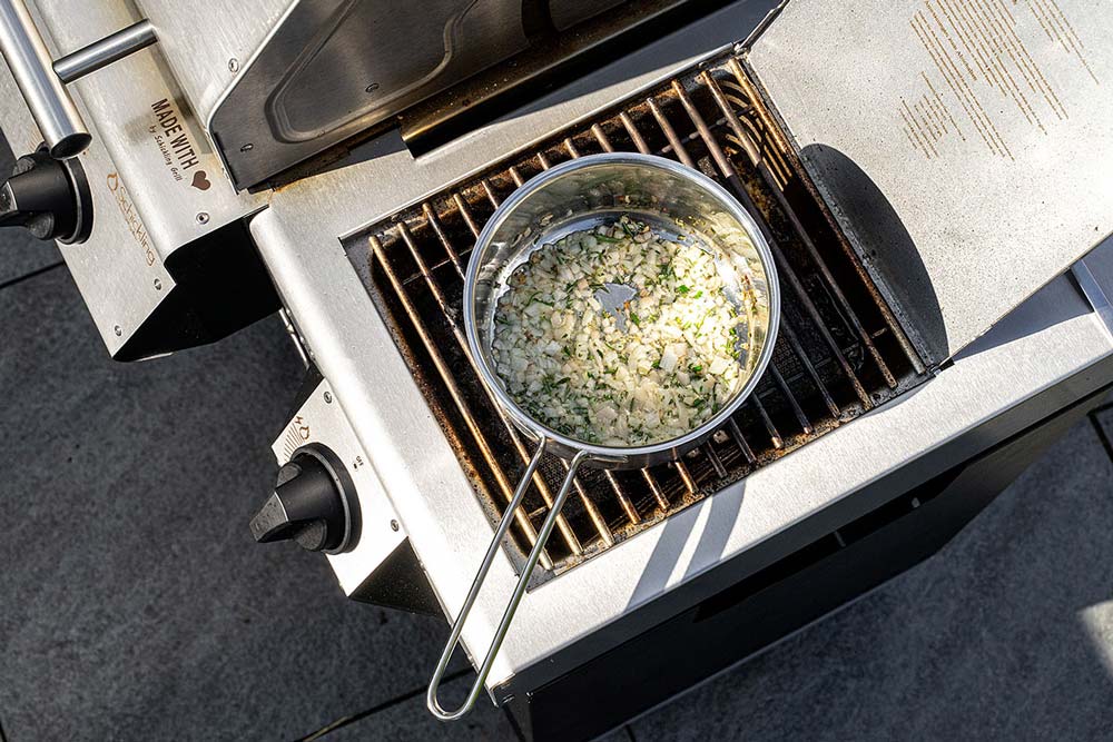 In einem mit gutem Olivenöl benetzten Kochtopf auf dem Seitenbrenner des Burners die Schalotten, unter Zugabe des Rosmarins anschwitzen.