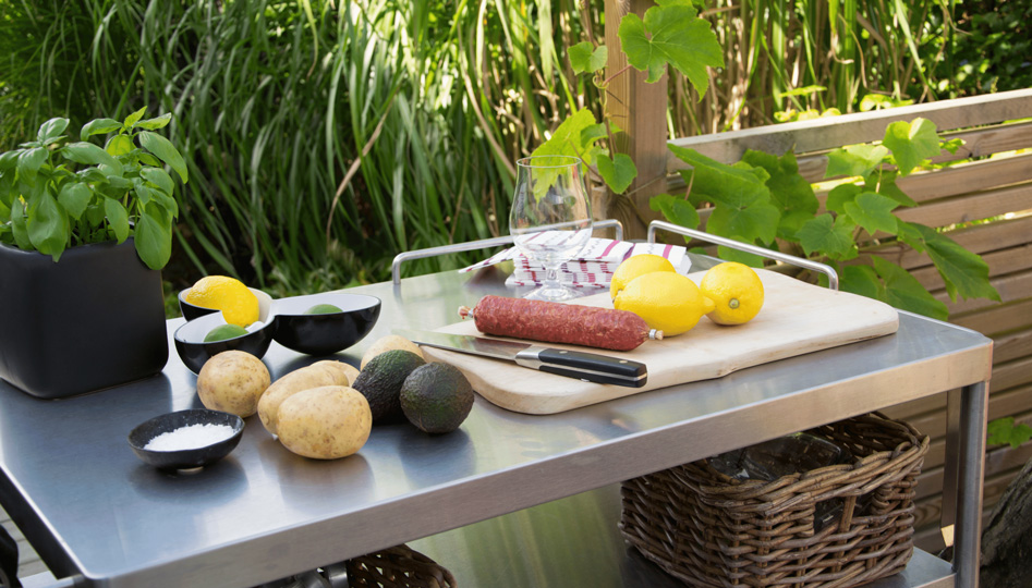 Was gehört in eine Outdoor Küche Titelbild. Ein Outdorrtisch mit verschiedenen Zutaten und Küchenutensilien