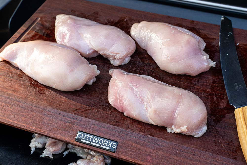 Zuerst teilen wir die Hähnchenbrustpaare und freien diese von überflüssigem Fett und Sehnen.