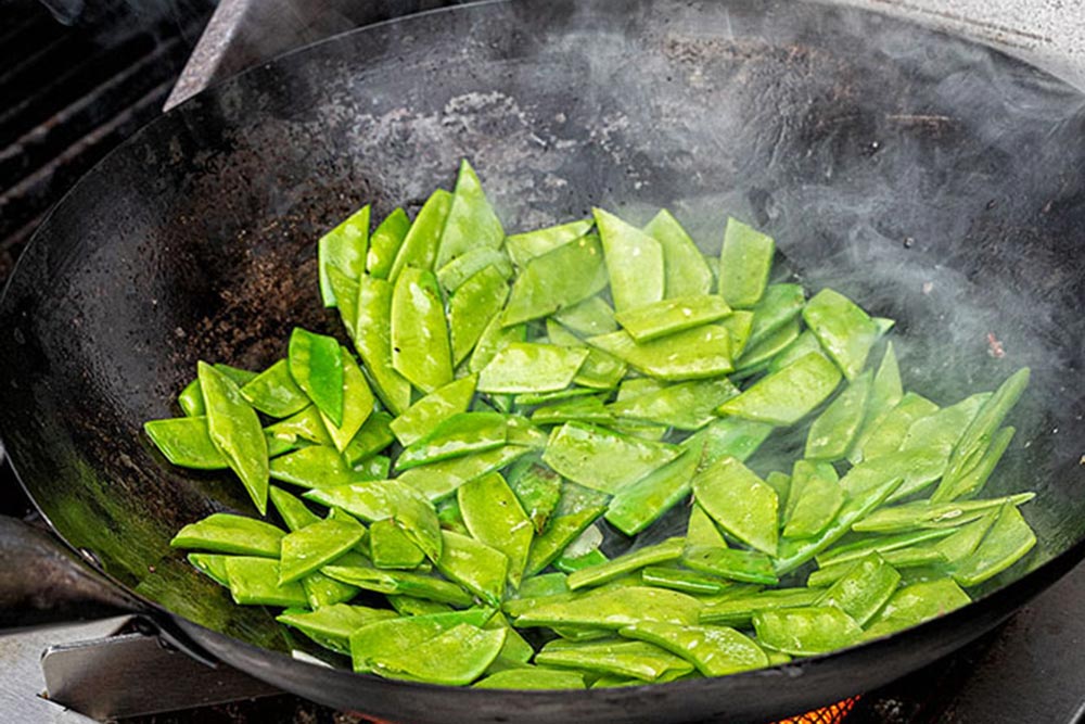 Die Zuckerschoten scharf anbraten, mit der Wok-Sauce ablöschen.