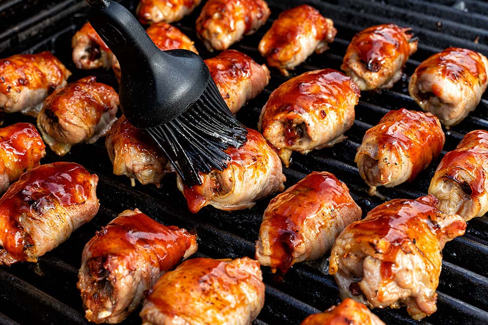 Kurz bevor der Bacon knusprig ist, die kleinen Röllchen mit der BBQ-Sauce bestreichen.