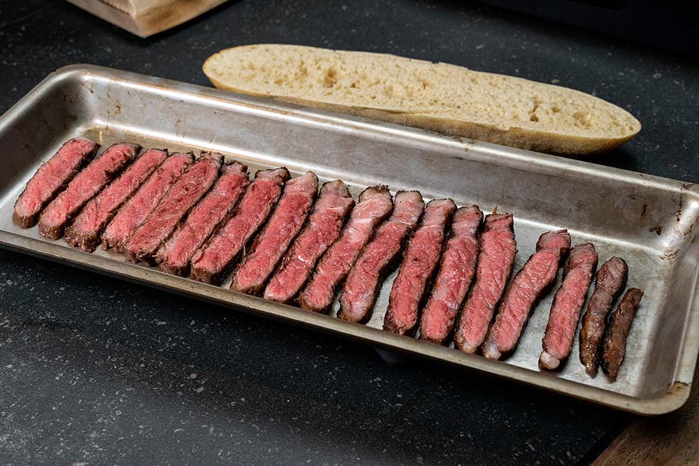 Wir legen die Steaktranchen in die erwärmte Grillschale. Dabei achten wir darauf, dass die Grillschale größer ist als das Baguette.