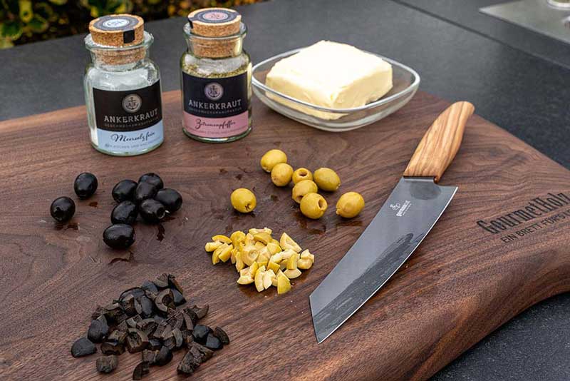 Die grünen und schwarzen Oliven achteln und die Butter, das grobe Meersalz und den Pfeffer bereitstellen.