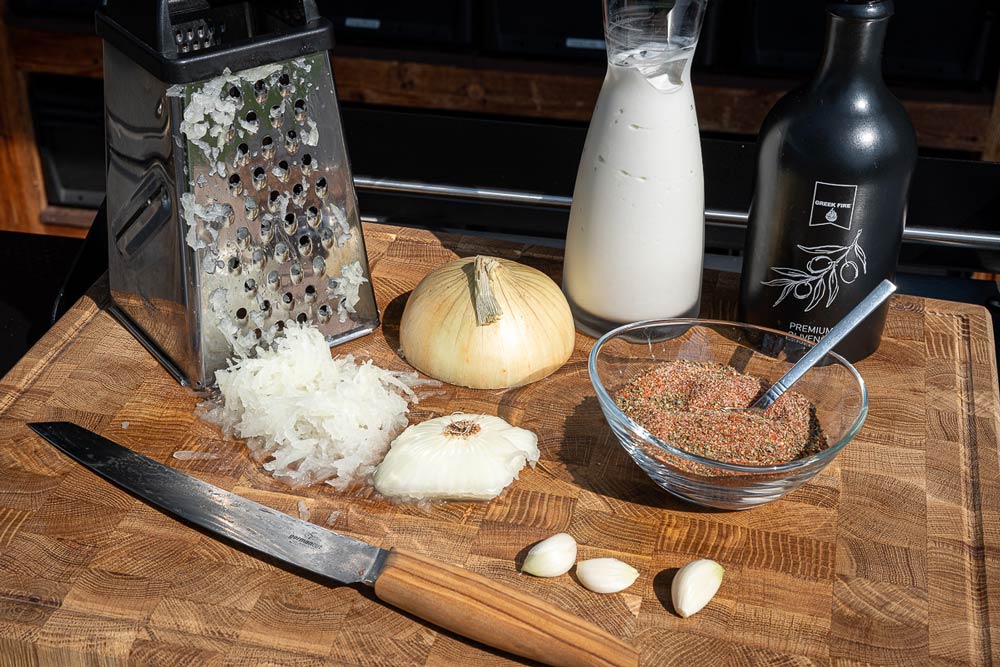 Gemüsezwiebel reiben, Knoblauch klein schneiden, Olivenöl und Joghurt bereitstellen.