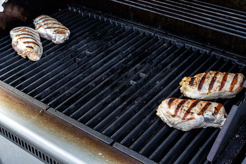 Wenn unsere Hähnchenbrüste sich gut vom Rost lösen und schöne Röstaromen angenommen haben, legen wir diese in den indirekten Bereich des Grills und regeln die Garraumtemperatur auf 150 Grad. So können die Hähnchenbrüste bis zur gewünschten Kerntemperatur gar ziehen.