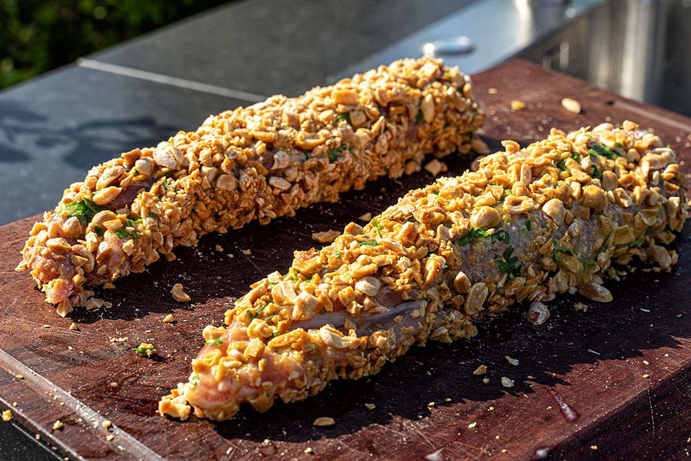 Zunächst die Schweinefilets in Mehl wälzen, anschließend durch die Petersilien-Eier ziehen und zu guter Letzt mit den gehackten Erdnüssen panieren.