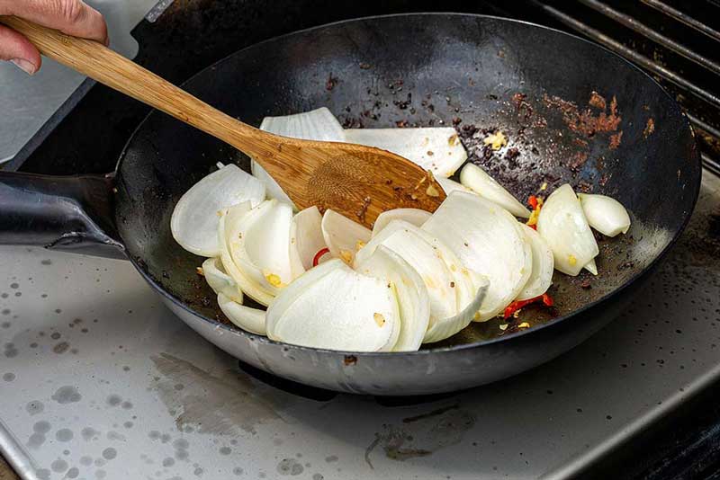 Das angebratene Fleisch aus dem Wok entnehmen und warm stellen. 
                    Den Wok mit einem EL Erdnussöl benetzen und anschließend den Knoblauch, 
                    Ingwer, Chili und die Gemüsezwiebel anschwitzen.