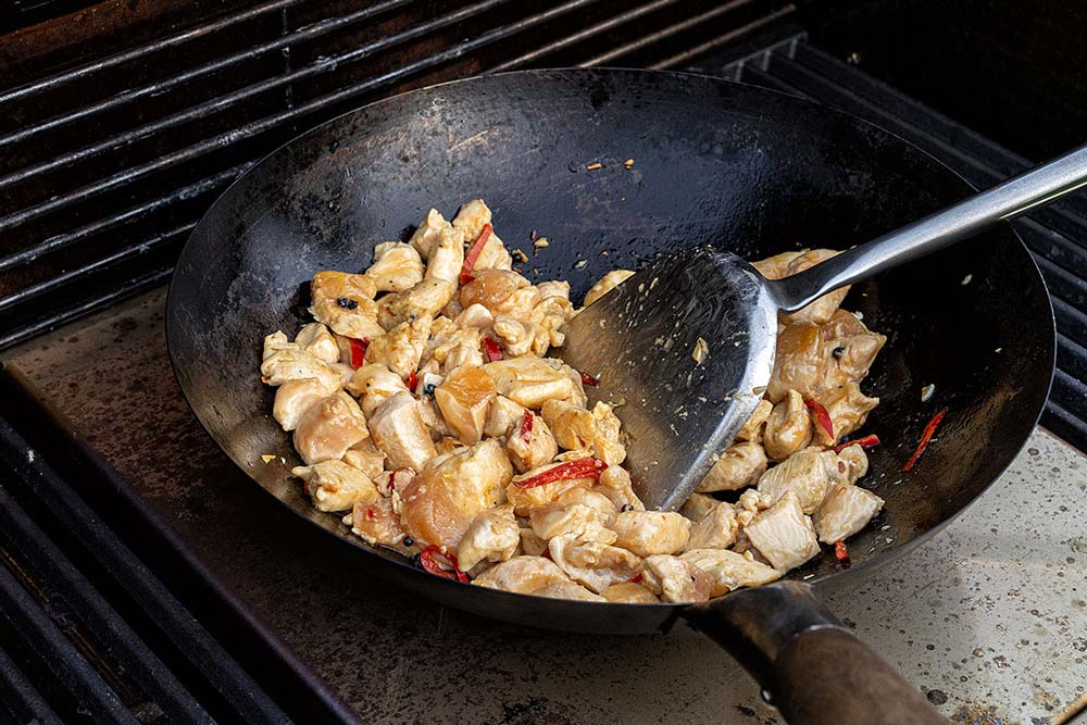 Die Chili-Mischung im Wok nach außen schieben und anschließend die Hähnchenbrust von beiden Seiten scharf anbraten.