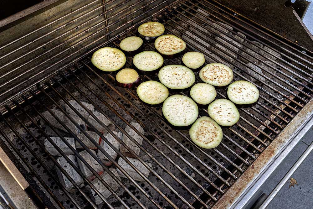 Überschüssiges Salz nach 15-20 Minuten abklopfen und Auberginen auf den Grillrost legen.