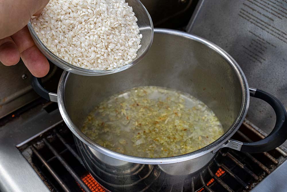 Anschließend löschen wir beides mit Weißwein ab und lassen diesen kurz aufkochen und geben dann den Risottoreis hinzu.