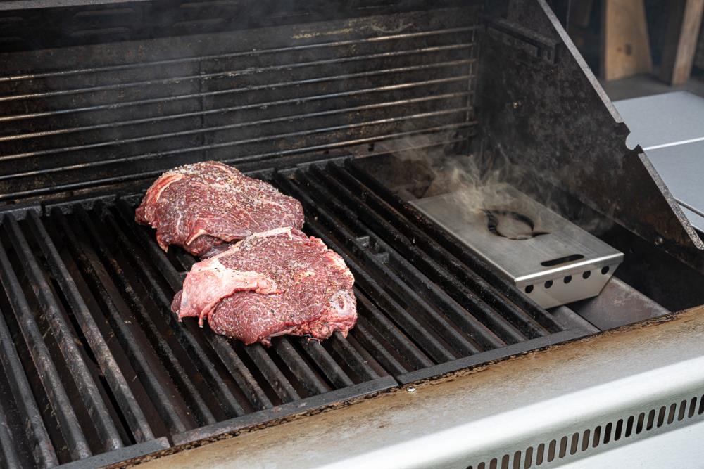 Die Räucherbox wird auf die Brennerabdeckungen oder in die Kohlewanne gestellt