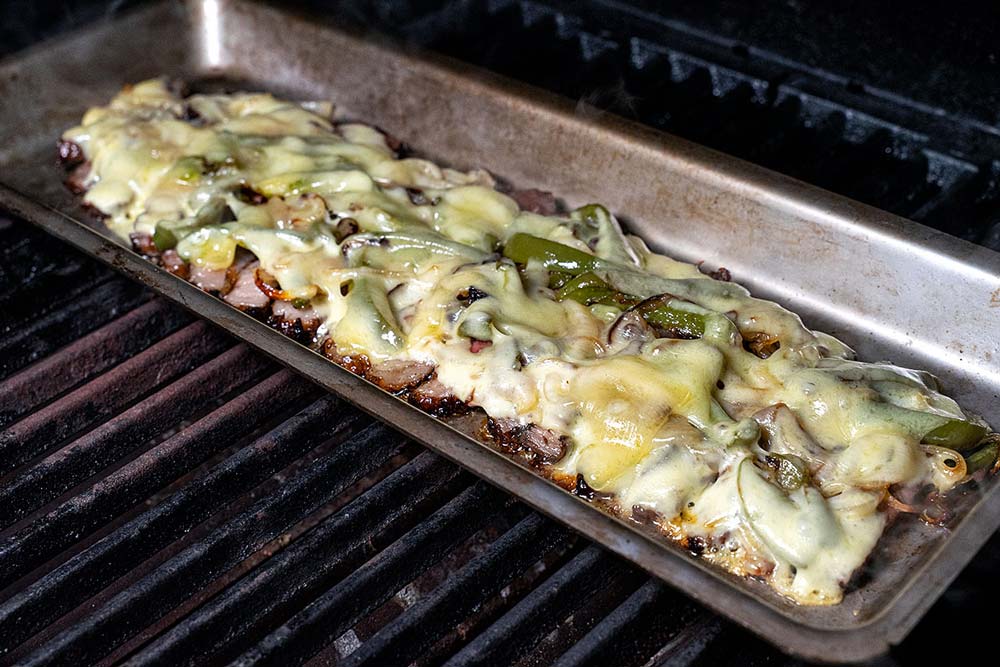 Währenddessen heizen wir den Grill maximal auf und stellen die Grillschale auf den Rost. So kann der Käse über dem Steak und Gemüse zerlaufen.