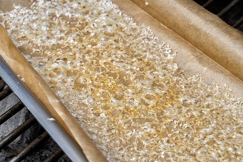 Grillschale in den indirekten Bereich des Grills stellen und Parmesan schmelzen lassen.