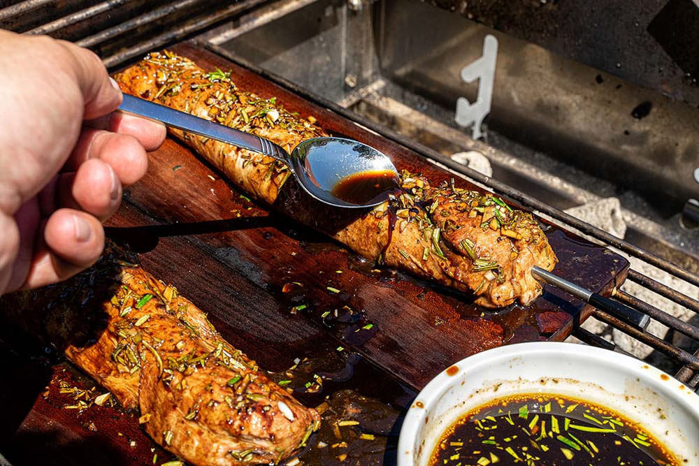 Während des Garens geben wir immer wieder etwas von der Marinade über die Schweinefilets.