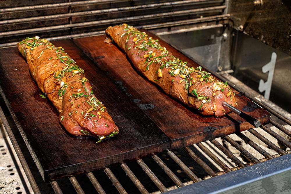 Die Holzplanken mit dem Schweinefilet im indirekten Bereich bei ca. 150 Grad mit geschlossenem Deckel garen.