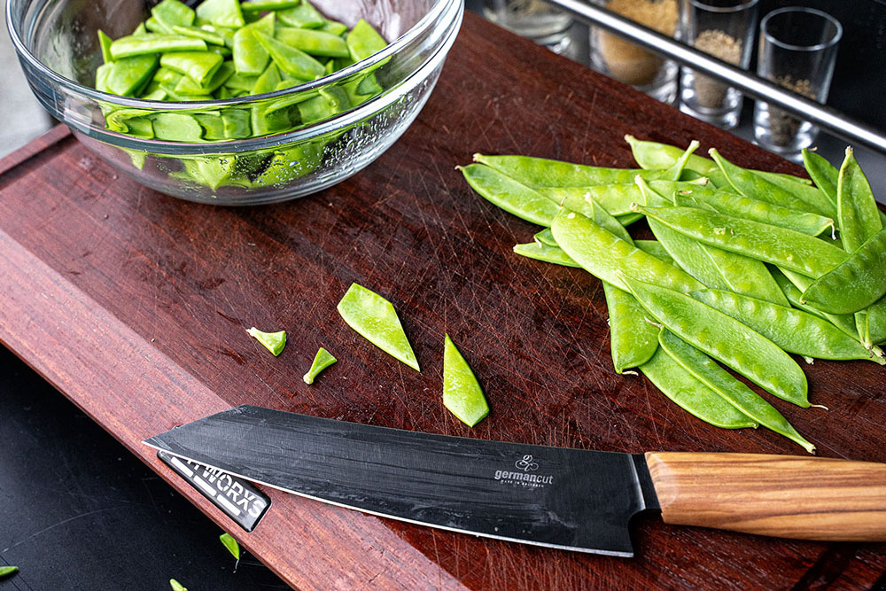 Die Enden der Zuckerschoten entfernen und durch einen schrägen Schnitt teilen.