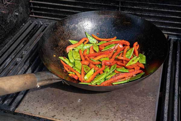 Die Paprika-Streifen sowie die Zuckerschoten hinzufügen und anschließend bei ständigem Rühren braten